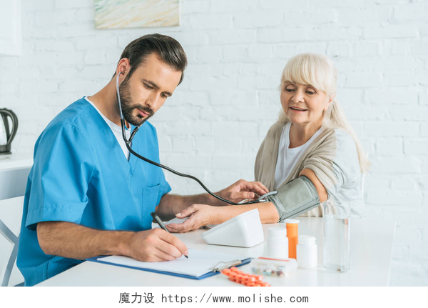 男医生给病人测量血压男性护士在听诊器写在剪贴板上, 同时测量老年妇女的血压